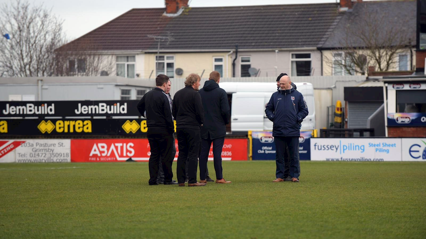 Groundsmen inspecting the pitch