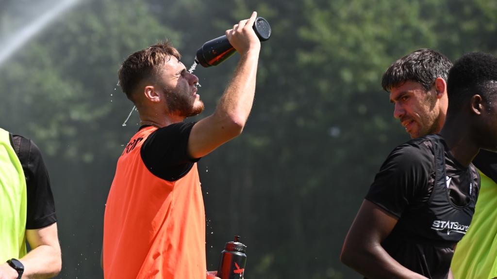 John McAtee empties a water bottle on his face in the hot weather